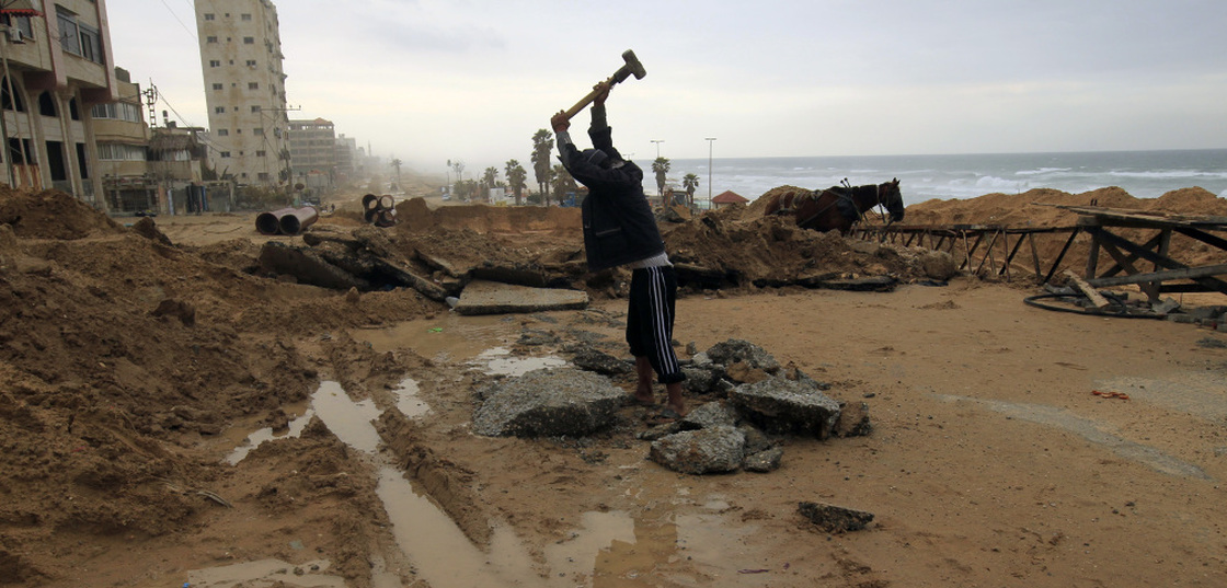 A Palestinian youth breaks up stones for construction in Gaza City. Despite restrictions on imports including building material, the area is going through a construction boom.