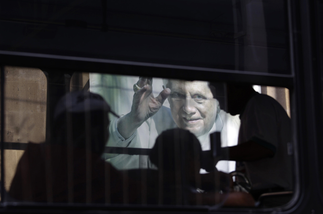 In this Feb. 29, 2012 photo, people riding on a bus pass a banner of Pope Benedict XVI on the wall of a church in Leon, Mexico.
