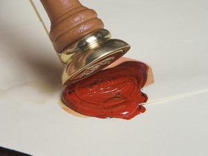 Envelope being closed and sealed with hot red wax Envelope being closed and sealed with hot red wax