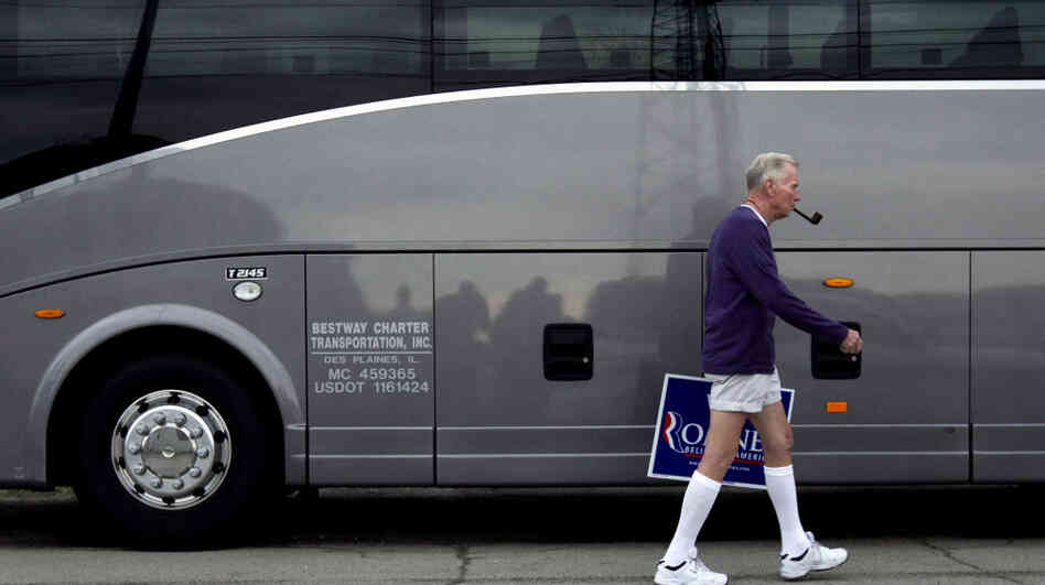 Jim Wilson of Buckingham, Va., who supports Republican presidential candidate Mitt Romney, walks past a bus during a Romney campaign stop Monday in Springfield, Ill.