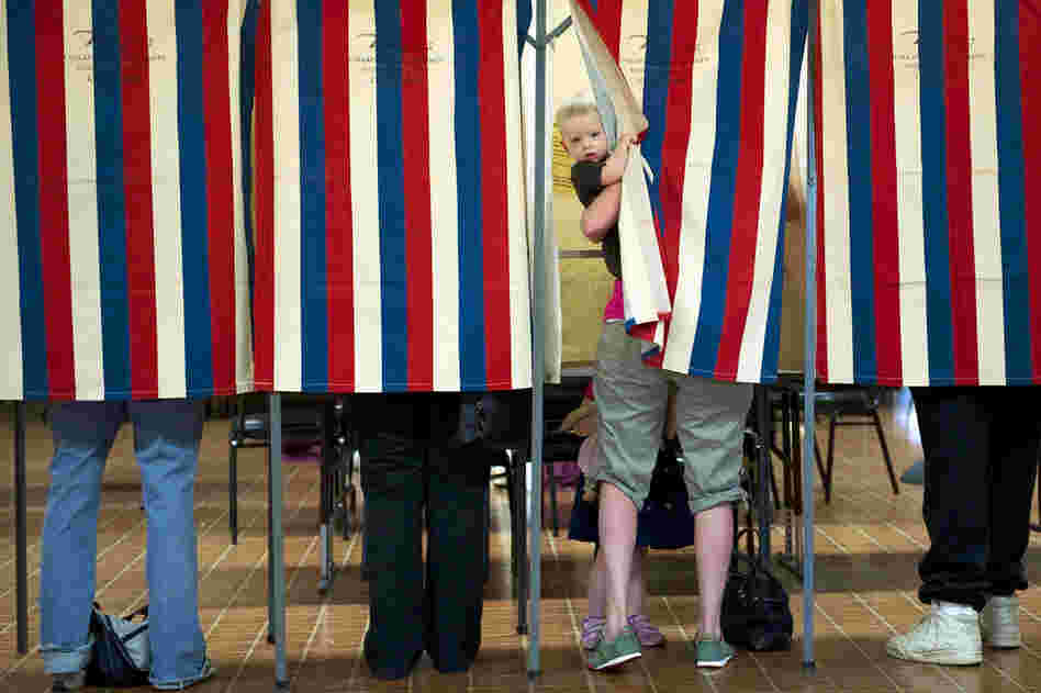 Landon Peterson peeks out of the voting booth while his mother, Meghan, votes in Metamora, Ill. 