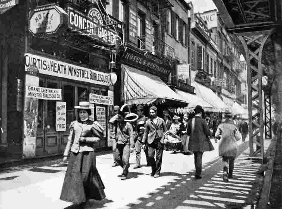 The Bowery, under the shadow of the elevated train tracks in New York City, bustled at night with colored lights and cane-swirling barkers, in places such as the Lyceum Concert Garden.