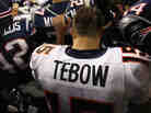 Tim Tebow of the Denver Broncos kneels and prays with teammates and members of the New England Patriots after the Patriots won 45-10 during their AFC Divisional Playoff Game at Gillette Stadium on January 14, 2012.