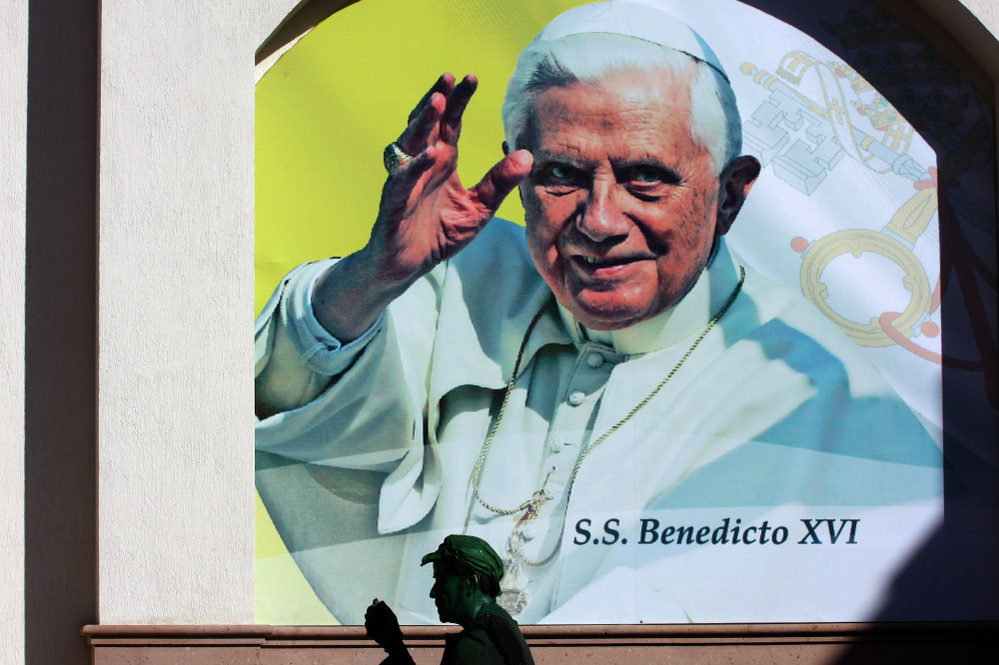 Pope Benedict XVI is expected to speak out against drug violence during his visit to Mexico, which begins Friday. Here, an actor is shown in front of a poster announcing the pope's visit Wednesday in the Mexican city of Leon, Guanajuato state.
