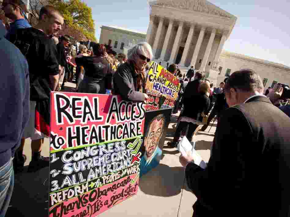 Amid a crowd of Tea Party activists, a supporter of President Obama's health care overhaul displays a sign outside the Supreme Court on Monday.