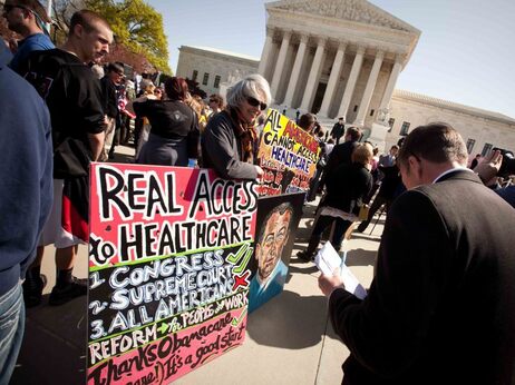Amid a crowd of Tea Party activists, a supporter of President Obama's health care overhaul displays a sign outside the Supreme Court on Monday. Amid a crowd of Tea Party activists, a supporter of President Obama's health care overhaul displays a sign outside the Supreme Court on Monday.