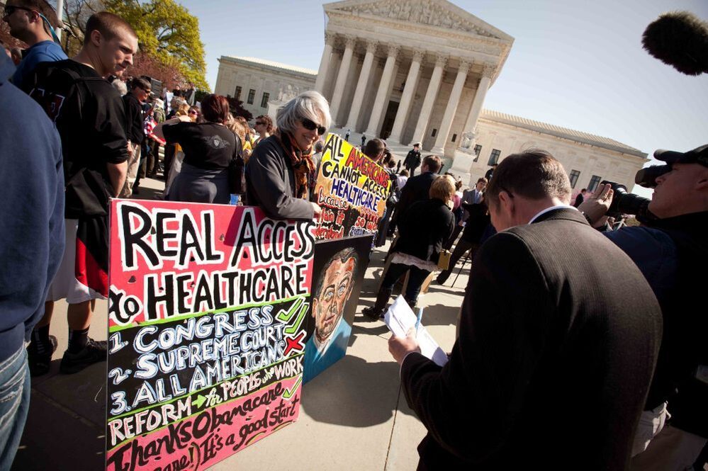 Amid a crowd of Tea Party activists, a supporter of President Obama's health care overhaul displays a sign outside the Supreme Court on Monday.