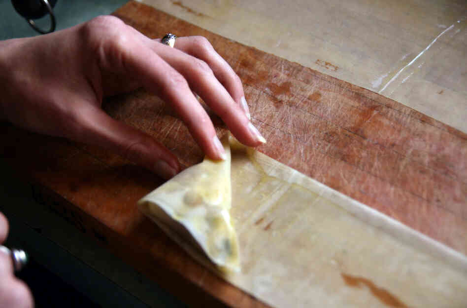 Sheets of phyllo are folded over the filling in a triangle shape, much like folding a flag. 