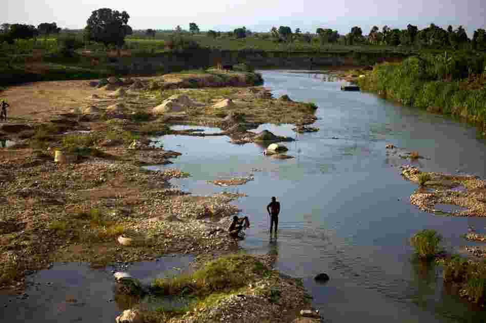 Men bathe in the evening in a branch of the Artibonite River outside Saint-Marc. Haiti's cholera outbreak began about 60 miles upstream from here. Well over a half-million have gotten sick.