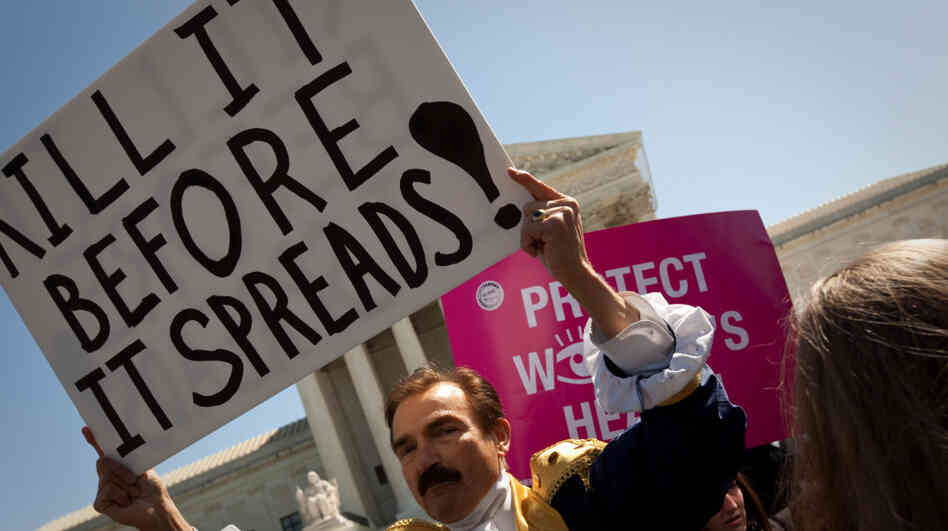 Opponents and supporters of President Obama's health care overhaul rallied outside the Supreme Court on Tuesday. Bob Mason shows support for the Tea Party by dressing in costume as one of the Founding Fathers.