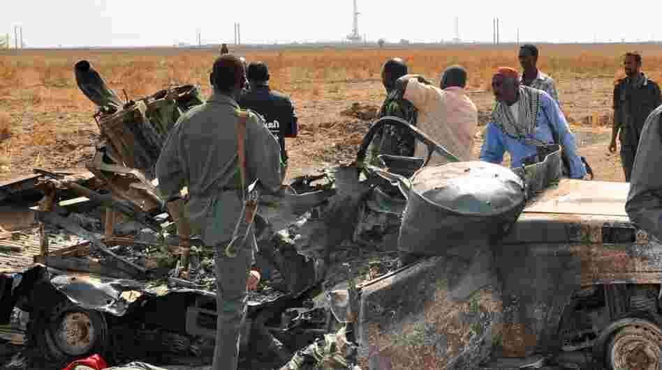 Sudanese troops stand next to a burnt-out military vehicle in the oil center of Heglig after clashes with South Sudanese forces Wednesday. Recent fighting has raised fears of a renewed war.