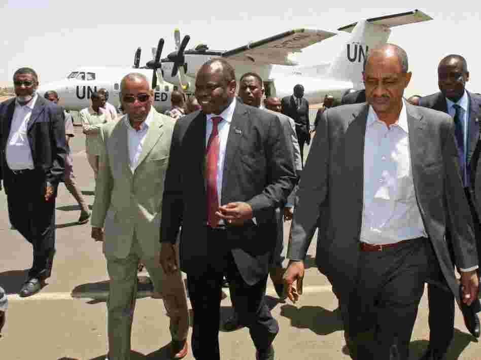  A delegation from South Sudan, headed by Pagan Amum (center), walks with Sudan's Idris Mohamed Abdul-Gadir (right) in Sudan's capital, Khartoum, on March 22. The delegation arrived for a summit between the leaders of the two countries, but the meeting was postponed due to recent tensions. 