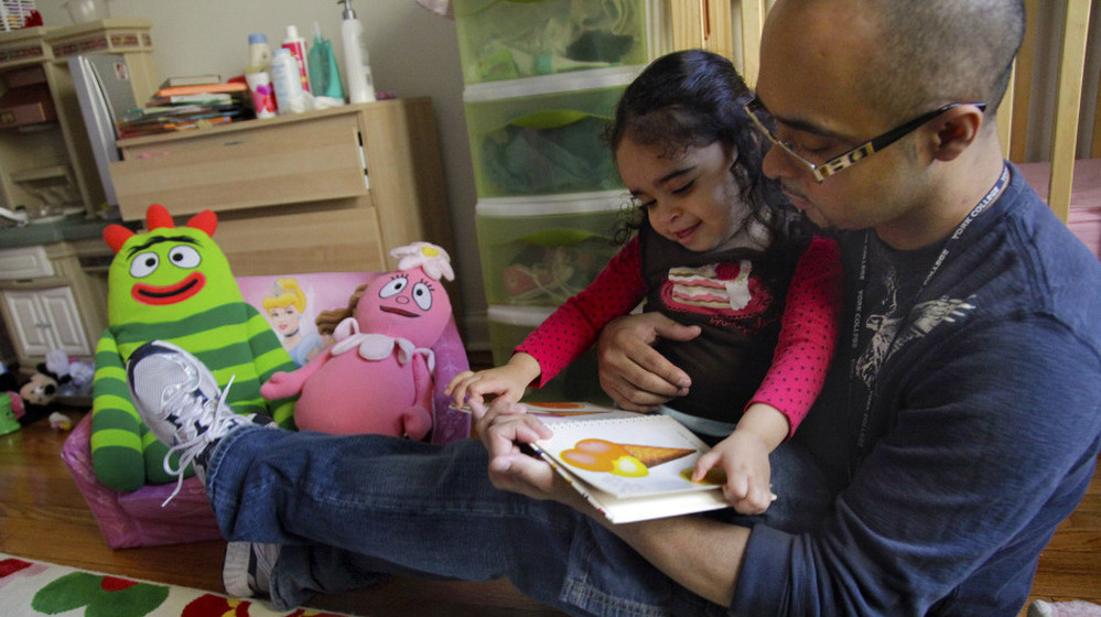 Christopher Astacio reads with his daughter Cristina, 2, recently diagnosed with a mild form of autism, in her New York bedroom on Wednesday. 