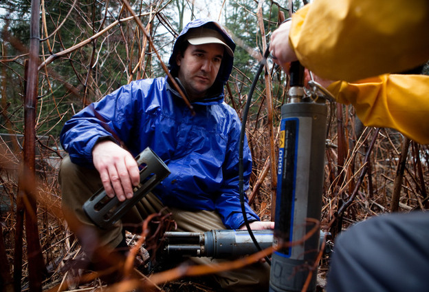 Andrew Gavin (left) of the Susquehanna River Basin Commission checks the readings from a device set up to monitor water quality at Gray's Run stream, near Williamsport, Pa.