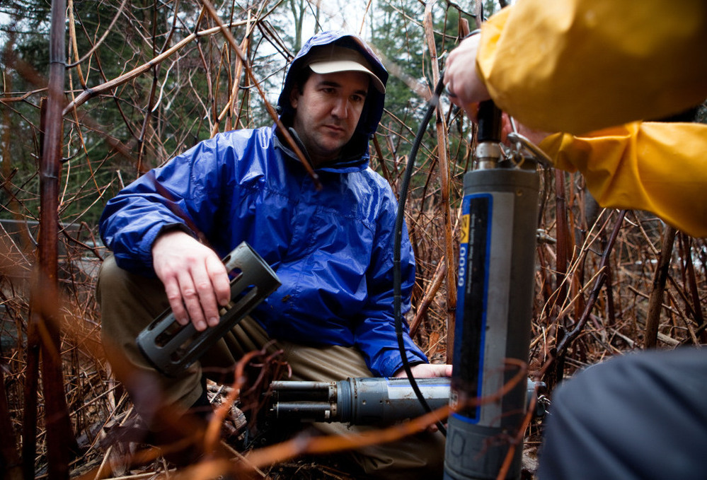 Andrew Gavin (left) of the Susquehanna River Basin Commission checks the readings from a device set up to monitor water quality at Gray's Run stream, near Williamsport, Pa.