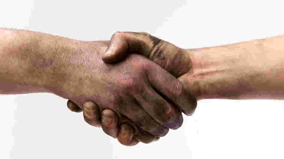 Two people with dirty hands shaking hands.