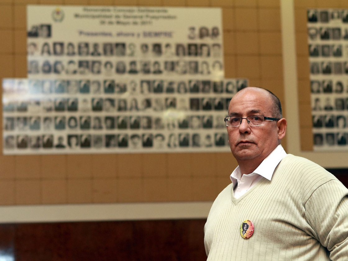 Human rights activist Carlos Diaz stands in Mar del Plata City Hall, where a wall displays portraits of the victims of a 1970s-era military dictatorship in Argentina.
