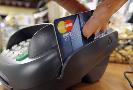 A customer swipes a MasterCard debit card through a machine while checking-out at a shop in Seattle. A customer swipes a MasterCard debit card through a machine while checking-out at a shop in Seattle.