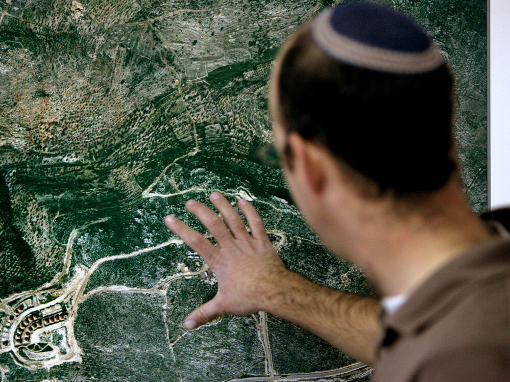 In this file photo, Israeli Amishai Shav-Tal, 31, one of the founders of the West Bank Jewish settlement of Bruchin, looks at an aerial photo of the settlement.