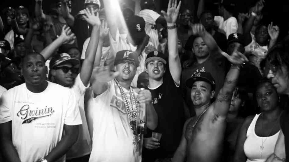 French Montana (in white shirt, chains and hat) and Harry Fraud (black shirt, black hat) at the center of the video for Montana's song "Shot Caller," which Fraud produced.