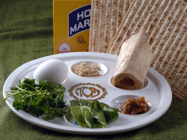 The Passover Seder plate with symbolic foods (clockwise, from top center): horseradish; a shank bone; a mixture of fruit, wine and nuts called haroset; lettuce, parsley and an egg. 