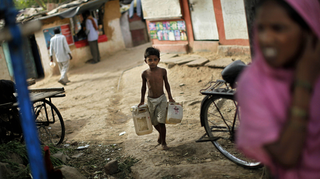 An Indian boy carries empty canisters to be filled at a water depot in a New Delhi slum. Data from India's latest census shows that although millions of Indians have access to technology such as TVs and cellphones, many millions more still lack basic amenities such as sanitation and water.