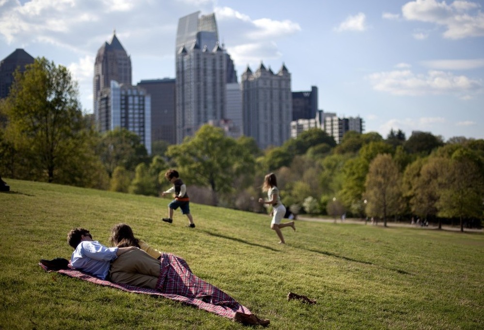 A couple enjoy a sunny afternoon against the backdrop of the Midtown skyline from Piedmont Park in Atlanta in late March.
