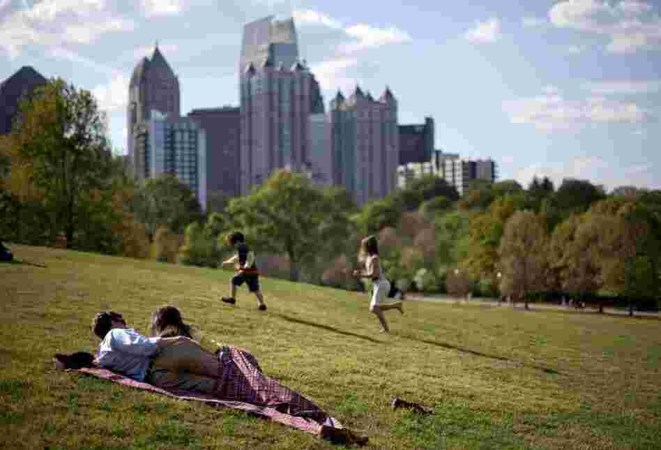 A couple enjoy a sunny afternoon against the backdrop of the Midtown skyline from Piedmont Park in Atlanta in late March.