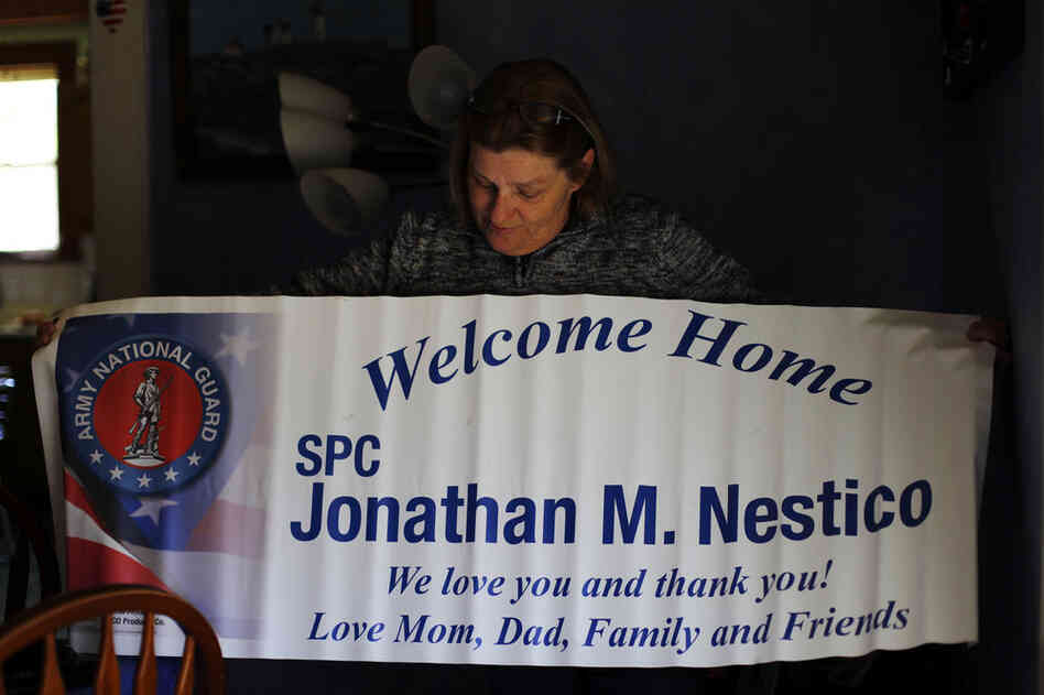 Judy holds up a welcome home banner from John's last noncombat deployment.