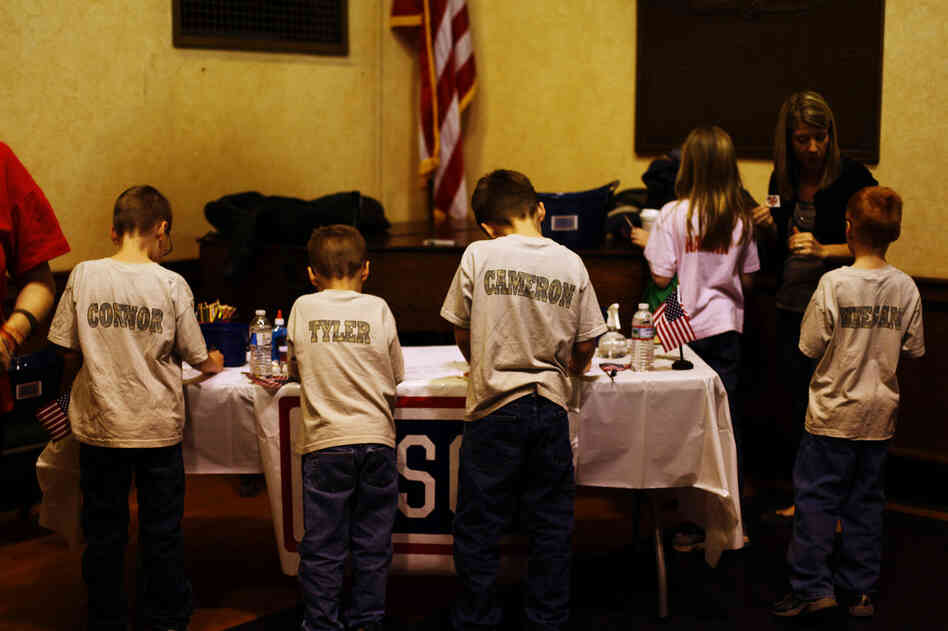 Connor, 10, Tyler, 7, Cameron, 9, Keegan, 9, and Hannah Butt, 10, decorate welcome home signs for their father, Jon, at the welcome home ceremony for the National Guard's 182nd Infantry Battalion in Melrose, Mass. 