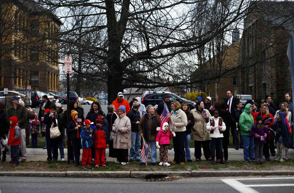Local residents lined the streets waving American flags and cheering as the four coach buses carrying the returning Guardsmen pulled up.