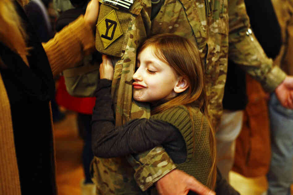 Gracelyn Currie, 7, hugs her father, Michael, at the conclusion of the welcome home ceremony.