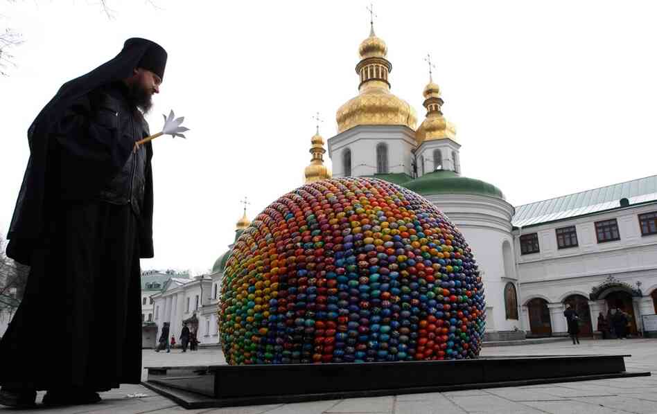 A priest peers at an egg sculpture built of 3,000 wooden eggs outside a cathedral in Kiev. 