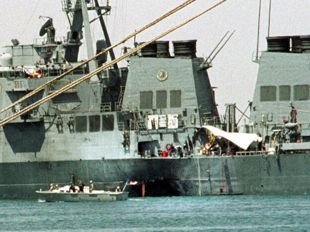 A small boat guards the USS Cole in Aden, Yemen, on Oct. 20, 2000. Abd al-Rahim al-Nashiri, the man accused of masterminding the attack, is expected to testify Wednesday in a courtroom at Guantanamo Bay.