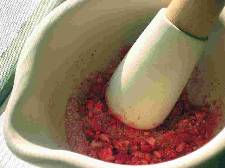 Sugar and dehydrated fruit are pulverized using a mortar and pestle.