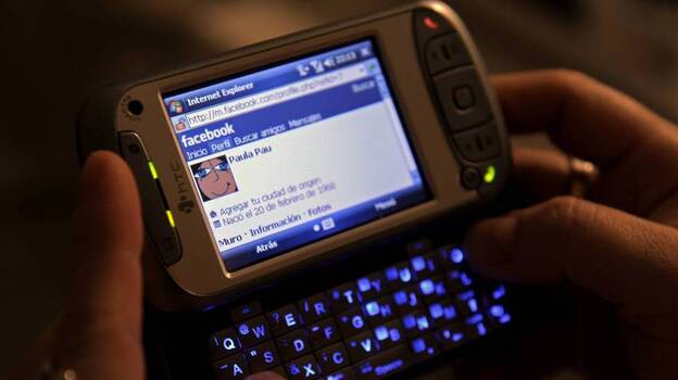 A woman uses her smartphone to access Facebook. Several states are close to banning employers from asking job applicants for their social media login information.