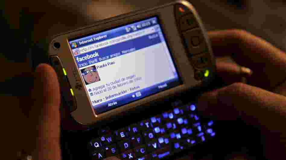 A woman uses her smartphone to access Facebook. Several states are close to banning employers from asking job applicants for their social media login information.