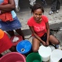  Marlene Lucien controls the hose that fills people's plastic buckets on one busy street corner in Port-au-Prince, Haiti.