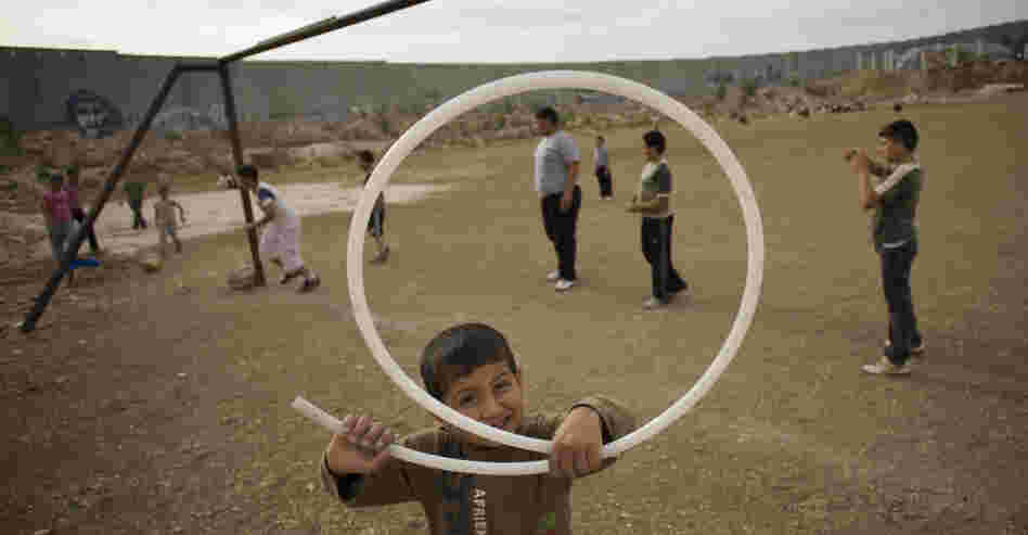 Palestinian children play next to Israel's separation barrier in the West Bank town of Abu Dis in 2011. As peace talks between Israel and Palestine remain at a standstill, people are looking to other possible solutions.