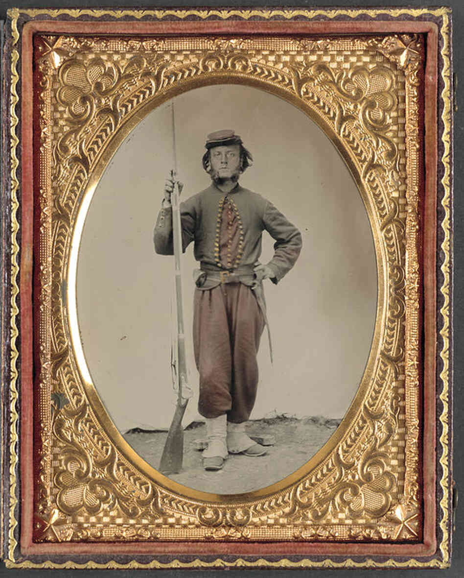 A tintype photograph shows an unidentified Union soldier at the time of the Civil War, standing with his bayoneted musket. 