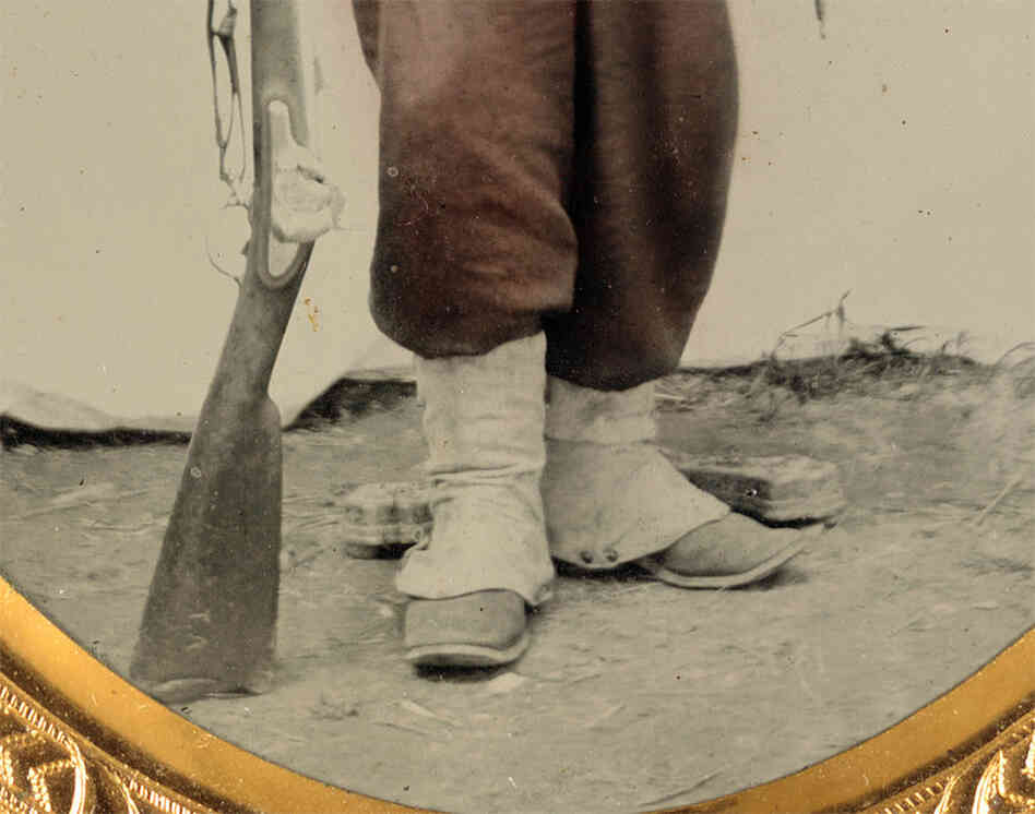 Zooming in on the image reveals that the stock of the soldier's rifle musket has two letters etched into it: "T.A." 