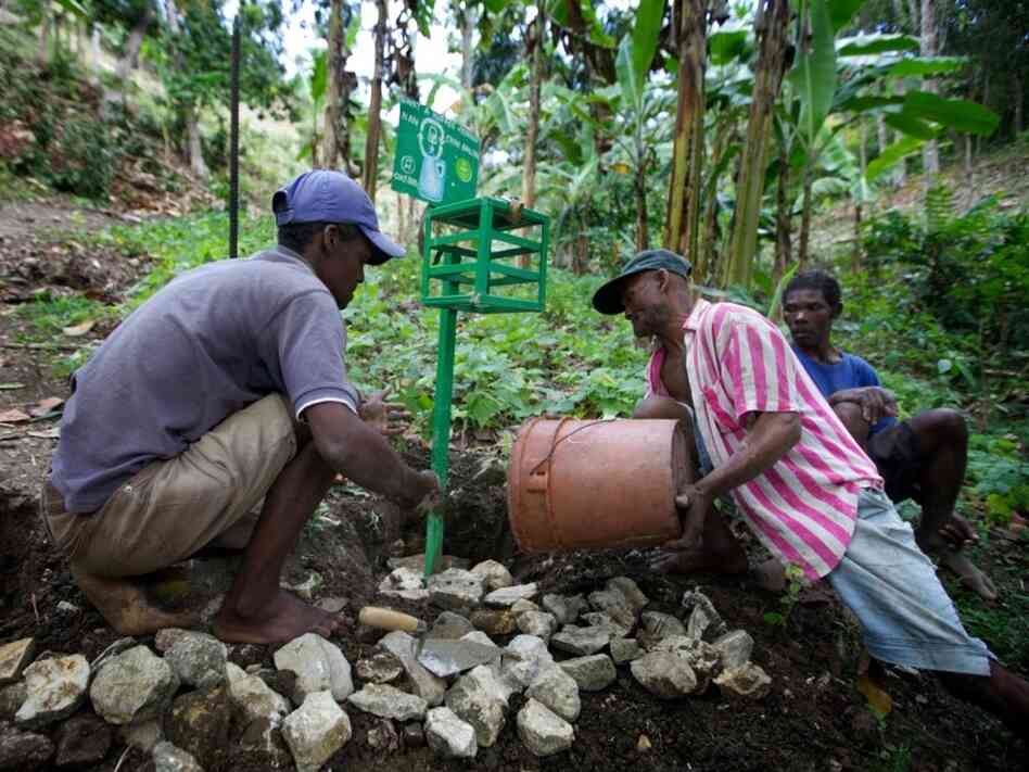 Men in the hillside village of Font de Liane in Haiti install a "chlorine box," a dispenser that adds just the right amount of chlorine to disinfect a five-gallon bucket of water. Cholera bacteria infect many streams in Haiti that people use for drinking, bathing and washing clothes. Men in the hillside village of Font de Liane in Haiti install a "chlorine box," a dispenser that adds just the right amount of chlorine to disinfect a five-gallon bucket of water. Cholera bacteria infect many streams in Haiti that people use for drinking, bathing and washing clothes.