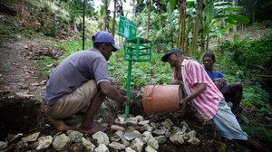 Men in the hillside village of Font de Liane in Haiti install a "chlorine box," a dispenser that adds just the right amount of chlorine to disinfect a five-gallon bucket of water. Cholera bacteria infect many streams in Haiti that people use for drinking, bathing and washing clothes.