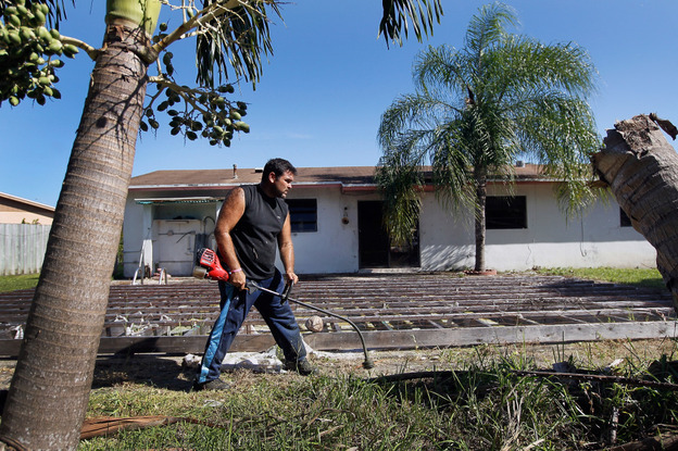 Renzo Salazar maintains the yard around a foreclosed house in Miami after the bank hired him to keep the home from falling into complete dilapidation. 