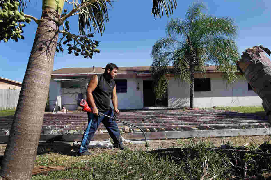 Renzo Salazar maintains the yard around a foreclosed house in Miami after the bank hired him to keep the home from falling into complete dilapidation. 