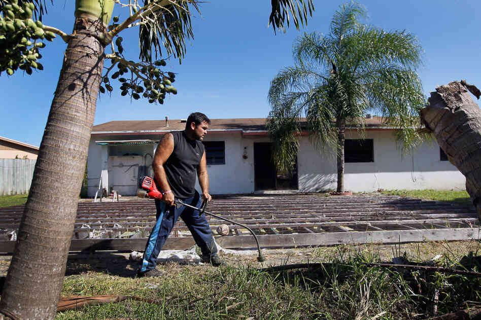 Renzo Salazar maintains the yard around a foreclosed house in Miami after the bank hired him to keep the home from falling into complete dilapidation. 