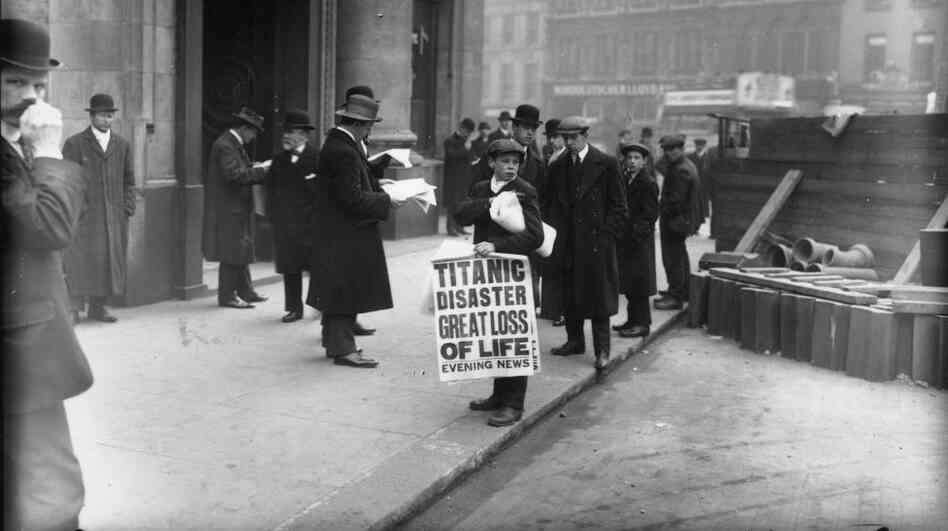 A London newspaper boy sells copies of the Evening News with a story about the sunken ship.