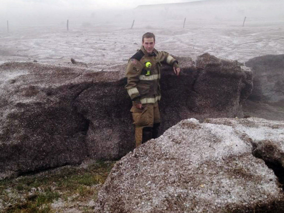 This photo provided by the Amarillo/Potter/Randall Office of Emergency Management shows Potter County firefighter Matt Dryden standing next to a wall of hail on Wednesday near Amarillo, Texas. The hail was pushed into drifts of up to 4-feet.