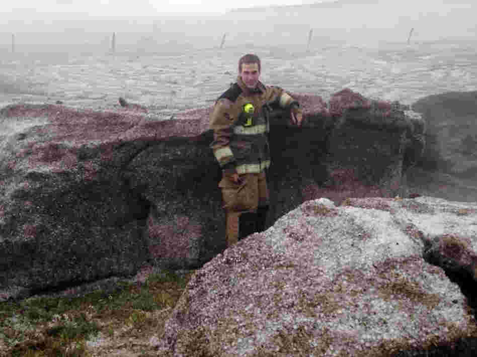 This photo provided by the Amarillo/Potter/Randall Office of Emergency Management shows Potter County firefighter Matt Dryden standing next to a wall of hail on Wednesday near Amarillo, Texas. The hail was pushed into drifts of up to 4-feet.