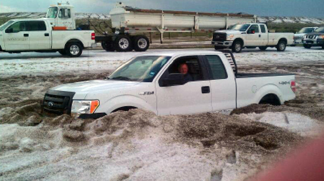 In this photo taken Wednesday and provided by the Amarillo/Potter/Randall Office of Emergency Management a motorist sits in a truck partially buried in slushy hail near Amarillo, Texas. 